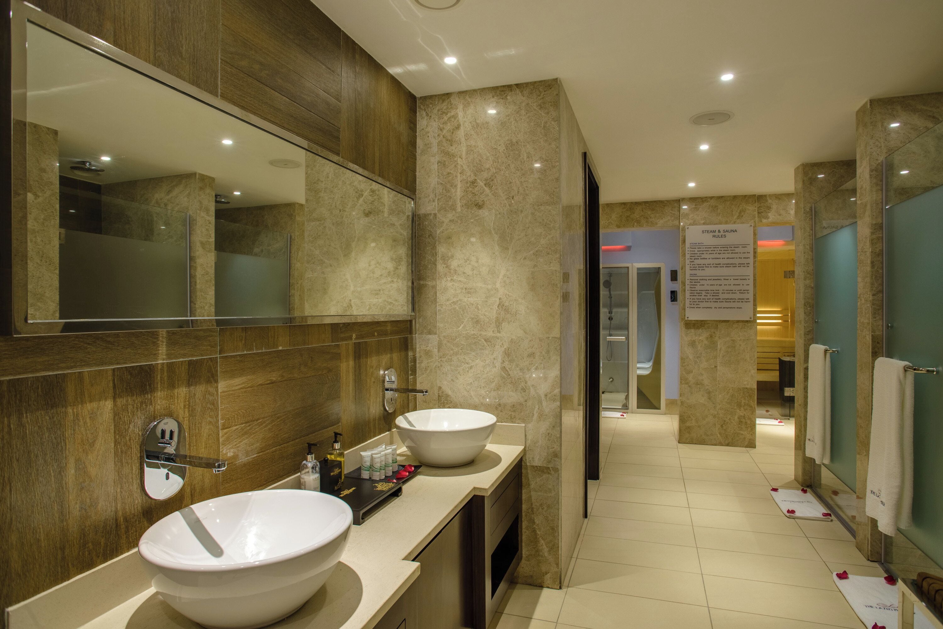A modern bathroom with two sinks, a large mirror, and a shower area.