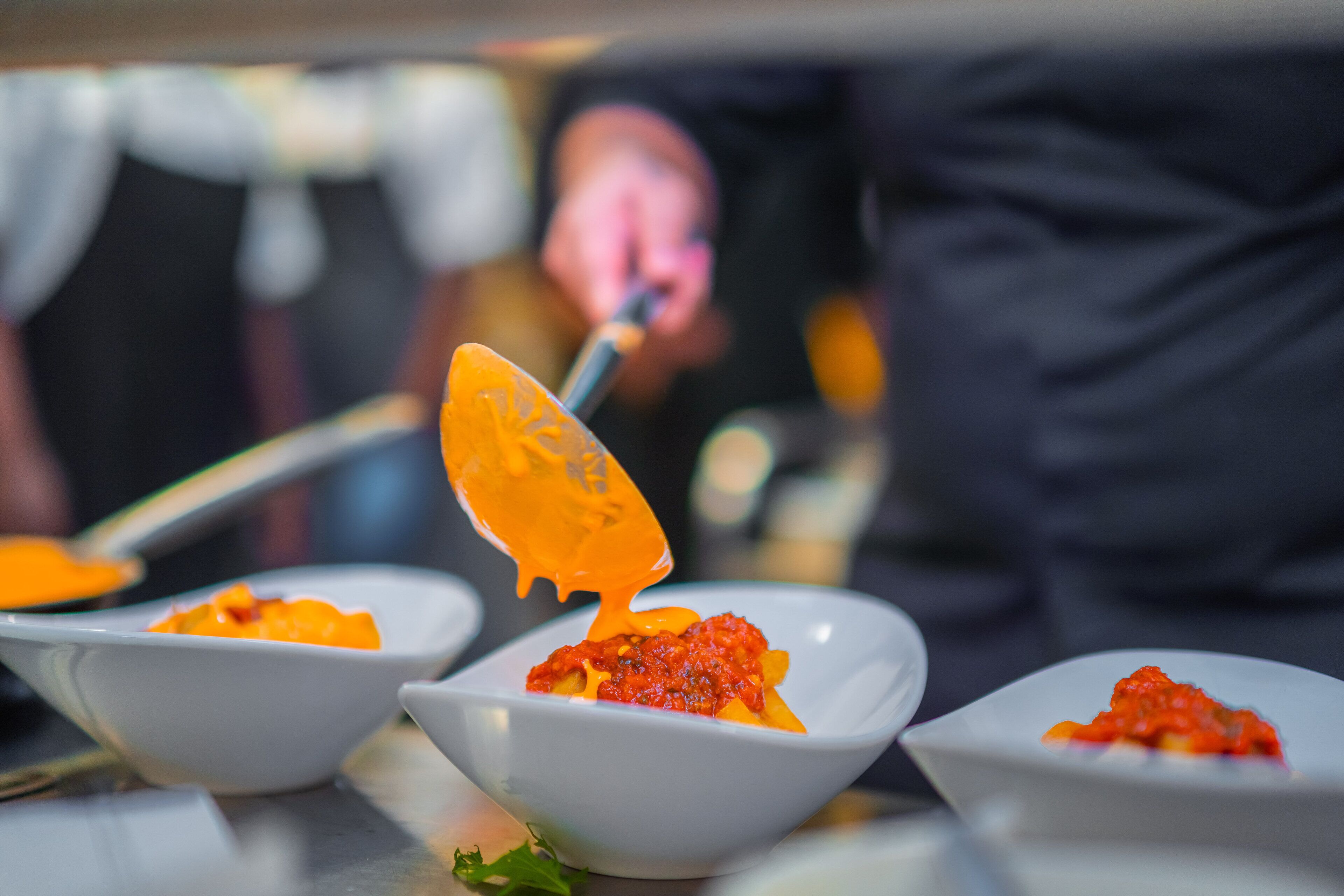 A close-up of a dish with a red sauce and a spoon lifting some of it.