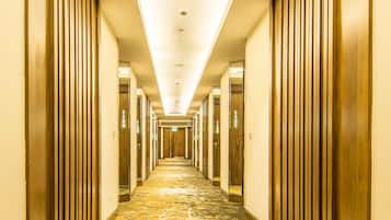 A long, narrow hallway with wooden paneling on the walls and a patterned carpet.