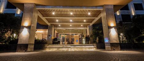A hotel entrance with a covered walkway, steps leading to the entrance, and a paved area in front.
