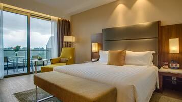 A hotel room with a large bed, a chair, a desk, and a view of the outdoors.