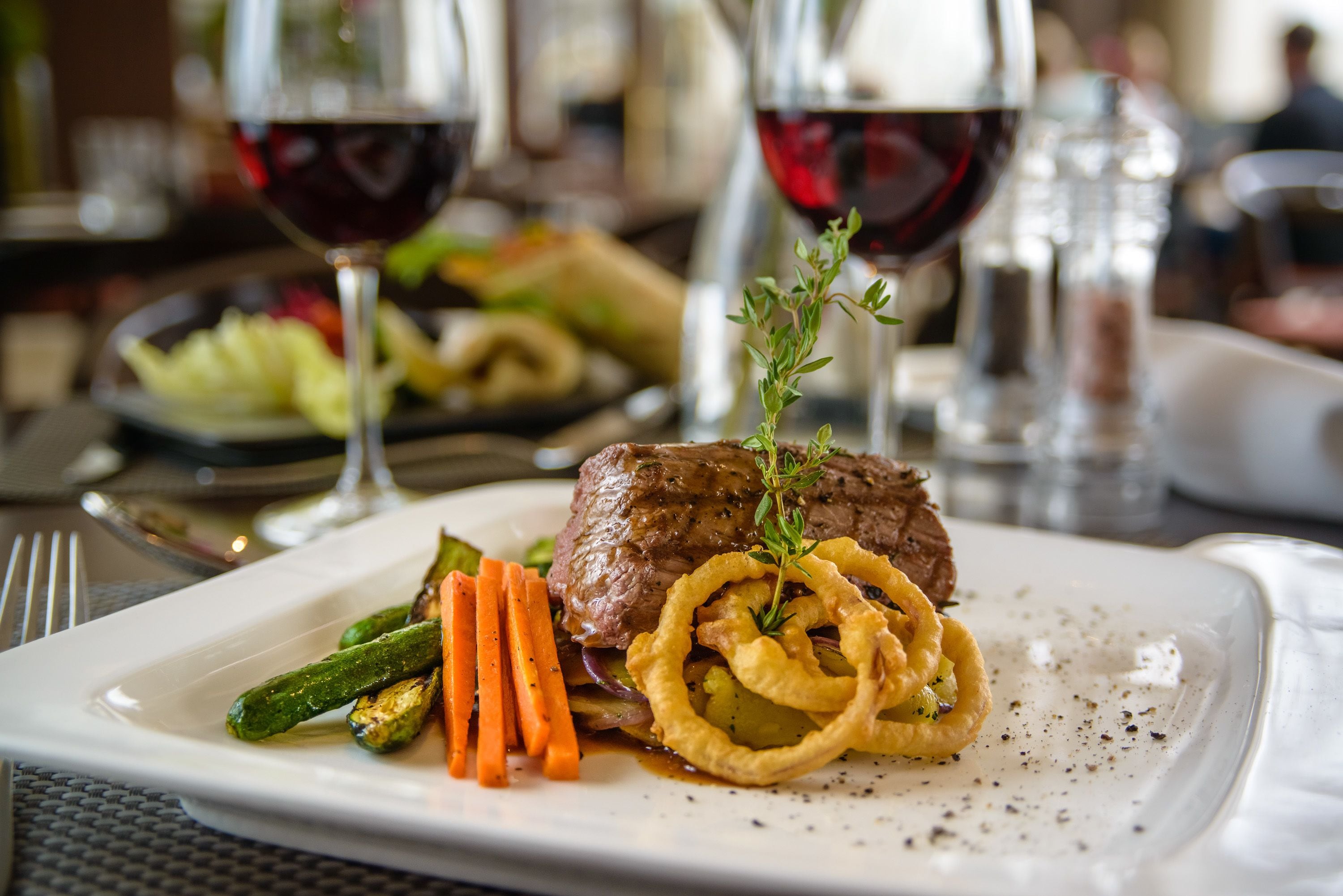 Une assiette de steak accompagnée de légumes et de rondelles d’oignon.