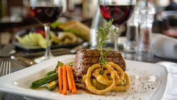 Une assiette de steak accompagnée de légumes et de rondelles d’oignon.