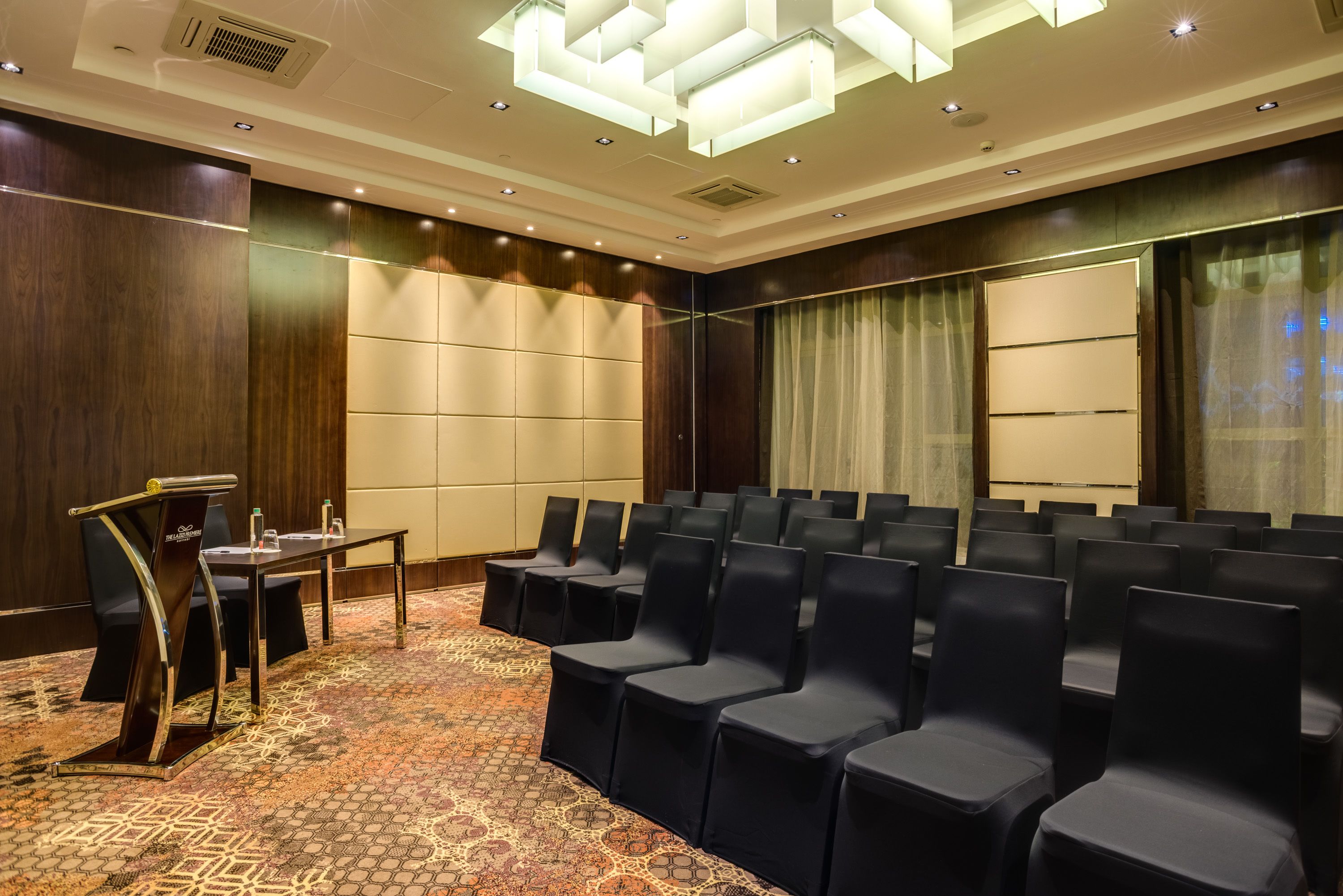A conference room with rows of chairs, a podium, and a carpeted floor.