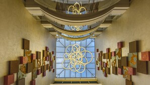 A modern interior with a central staircase, geometric wall art, and a unique ceiling design. - Crowne Plaza Nairobi Airport by IHG (Nairobi)