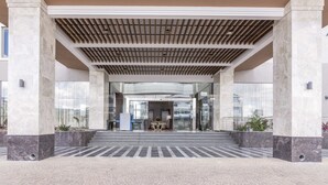 A modern building entrance with a covered walkway, marble columns, and a seating area with a table and chairs. - Crowne Plaza Nairobi Airport by IHG (Nairobi)