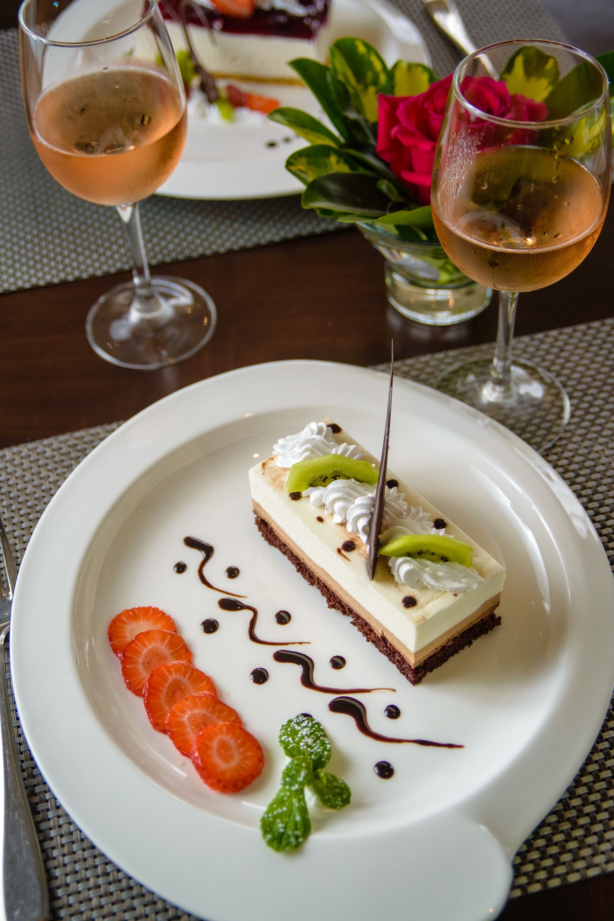 A dessert plate with a slice of cake, strawberries, and mint leaves.