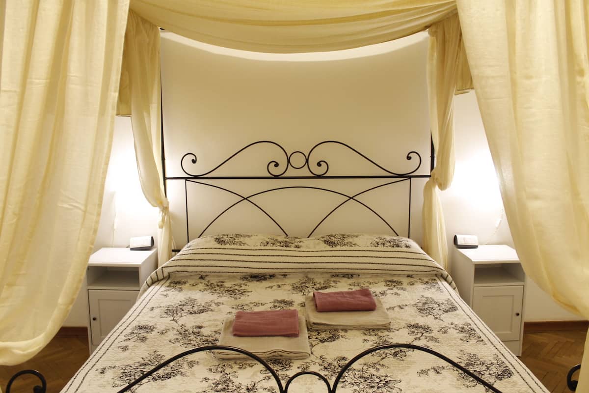 A bed with a canopy, two nightstands, and a bedside table.
