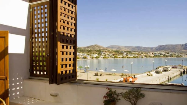 Una stanza con vista su un porto turistico, una piscina e montagne in lontananza.