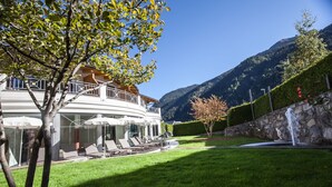 Ein modernes Haus mit Balkon, einem gepflegten Rasen und Blick auf die Berge.