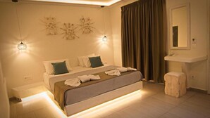 A modern bedroom with a large bed, bedside lamps, a vanity, and a mirror. - Santorini Breeze (Santorini)