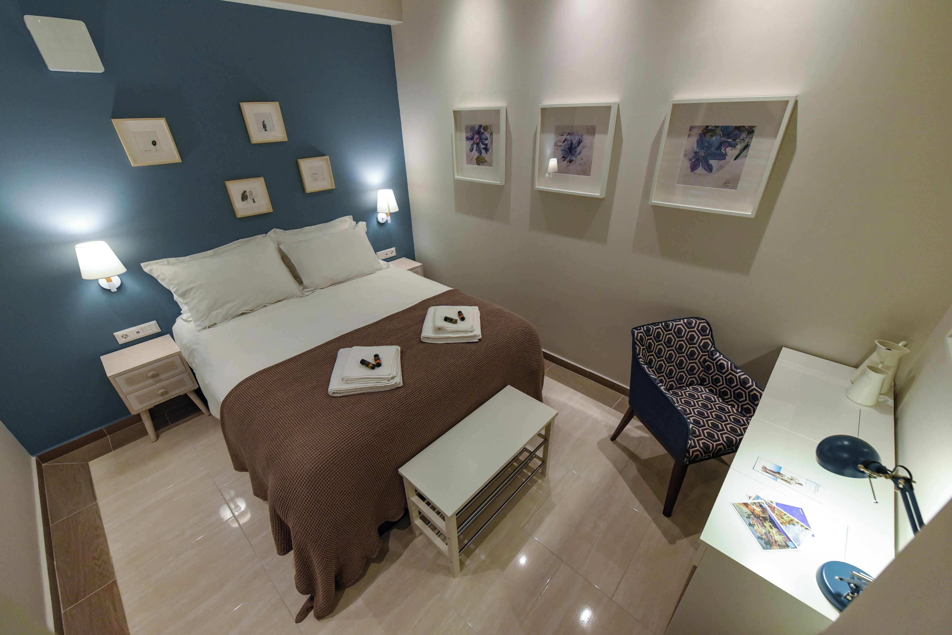 Habitación de hotel con cama, mesitas de noche, escritorio con silla y obra de arte en la pared.