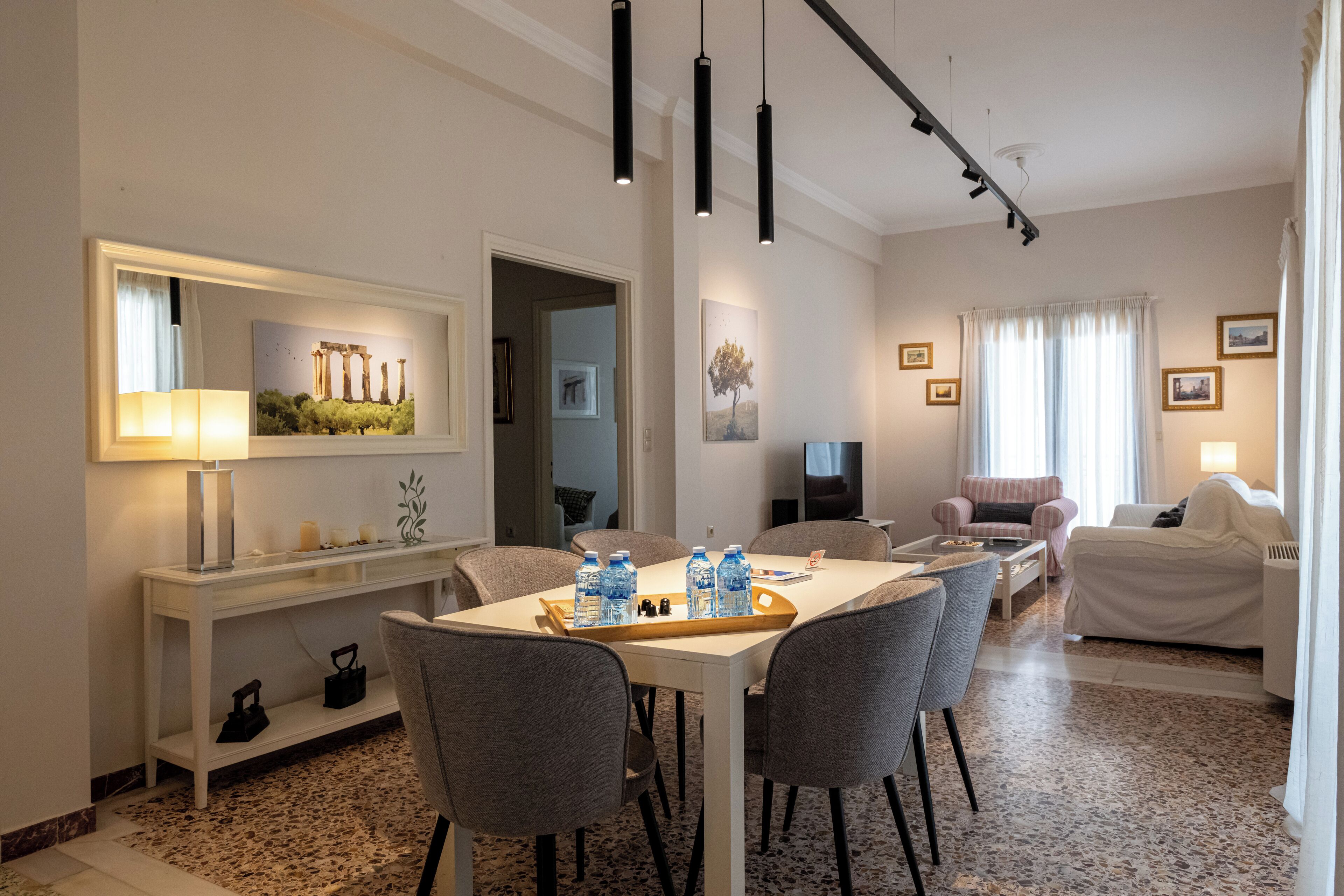 Une chambre d’hôtel comprenant un coin repas, un salon et une grande fenêtre avec des rideaux.