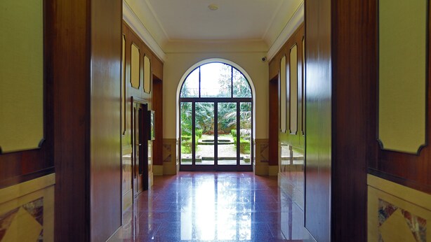 A hallway with a large arched window leading to a garden. - Tata B&B (Rome)