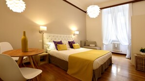 A modern bedroom with a bed, bedside tables, a chair, a table, and a window with curtains. - Tata B&B (Rome)