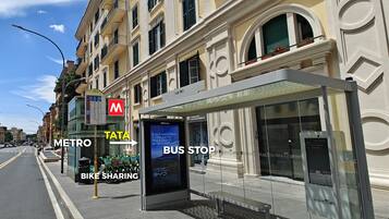 A bus stop with a shelter, a sign for the metro, and a bike-sharing station.