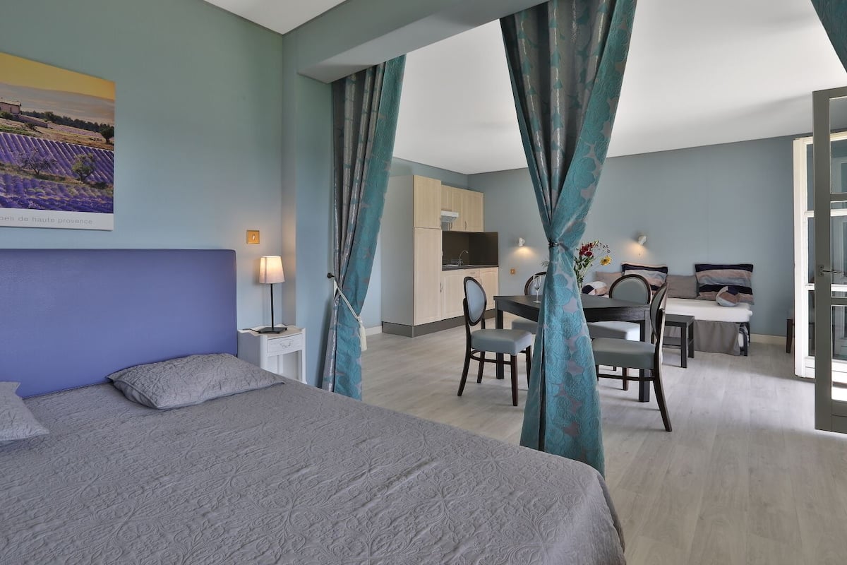 A modern hotel room with a large bed, a desk, and a dining table.