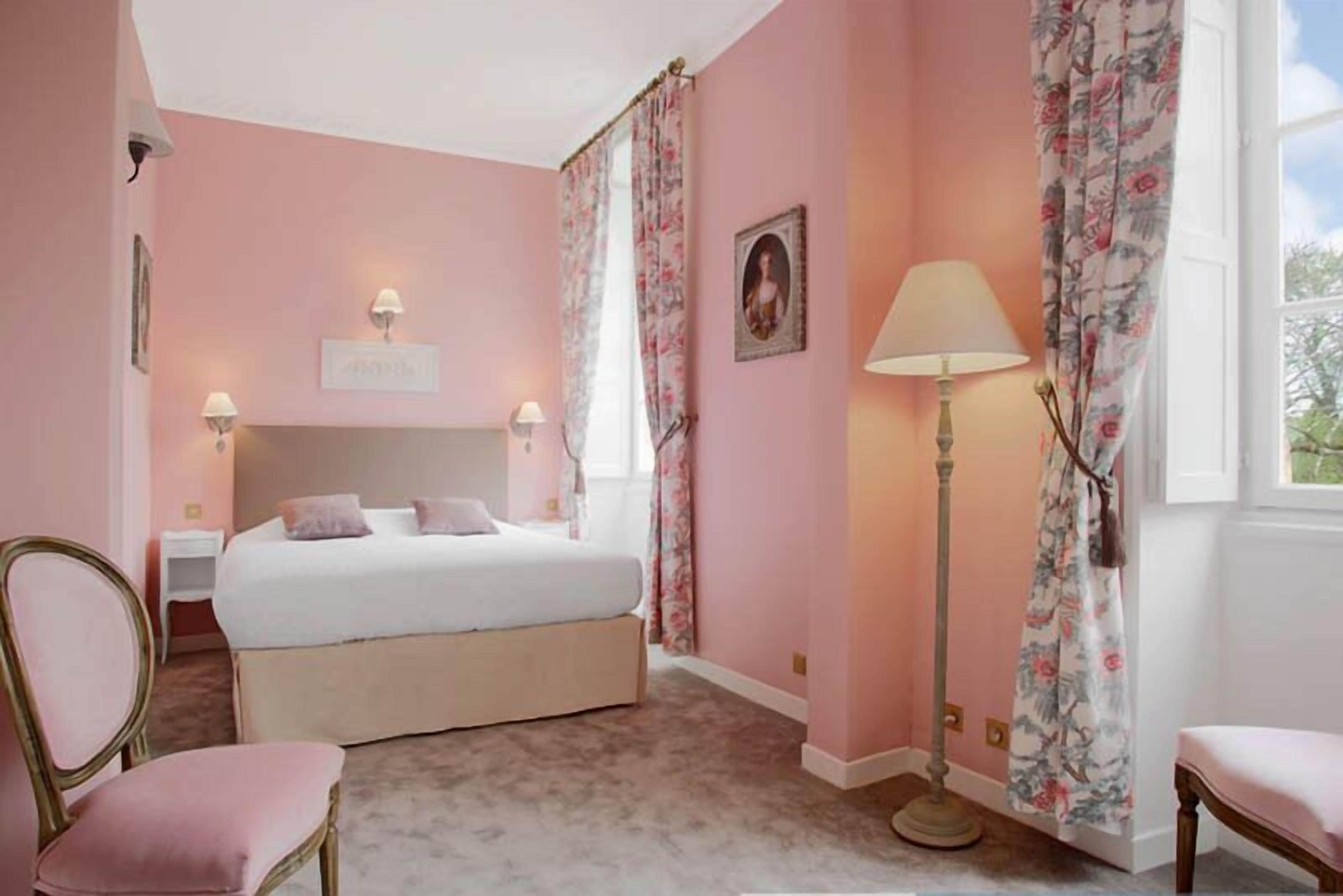 A bedroom with a bed, a chair, a floor lamp, and curtains.