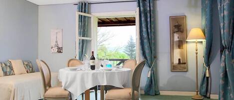Un comedor con una mesa redonda preparada para cuatro personas, un sofá y una araña.