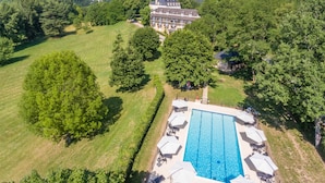Vista aérea de un hotel con piscina, rodeado de exuberante vegetación y árboles.