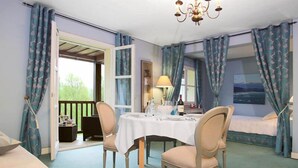 Una habitación con mesa de comedor preparada para cuatro, cama con vistas y ventana con cortinas.