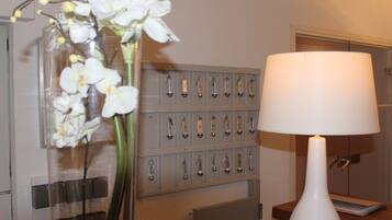 A room with a white lamp, a key rack, and a vase with white flowers.