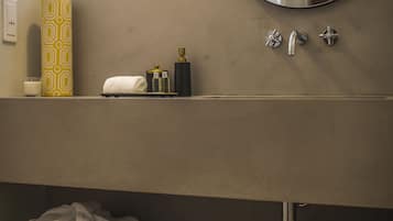 A bathroom with a round mirror, a towel rack, and a shelf with toiletries.