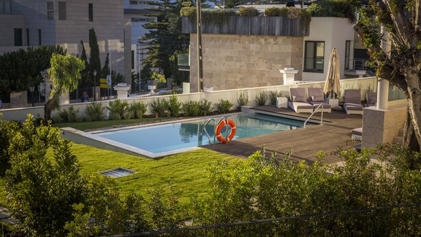 Una piscina en la azotea con terraza de madera, sillas de descanso y un flotador.