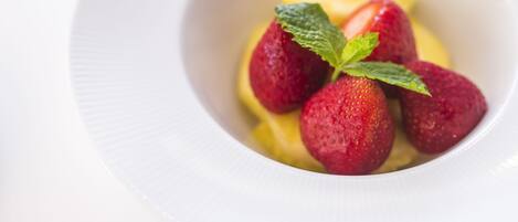 A white bowl containing strawberries and a slice of lemon.