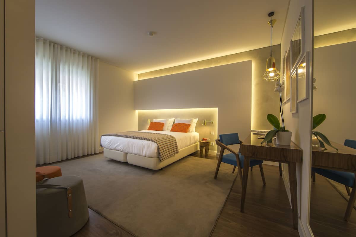 Una habitación de hotel moderna con una cama grande, una mesa de comedor y una pequeña mesita auxiliar.