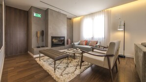 Una sala de estar moderna con un sofá, un sillón, un reposapiés y un televisor de pantalla plana.
