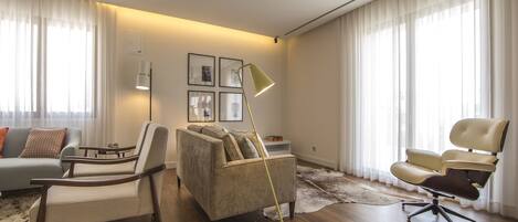 A modern living room with a sofa, two armchairs, a floor lamp, and a rug.