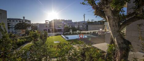 A courtyard with a swimming pool, surrounded by buildings and greenery.