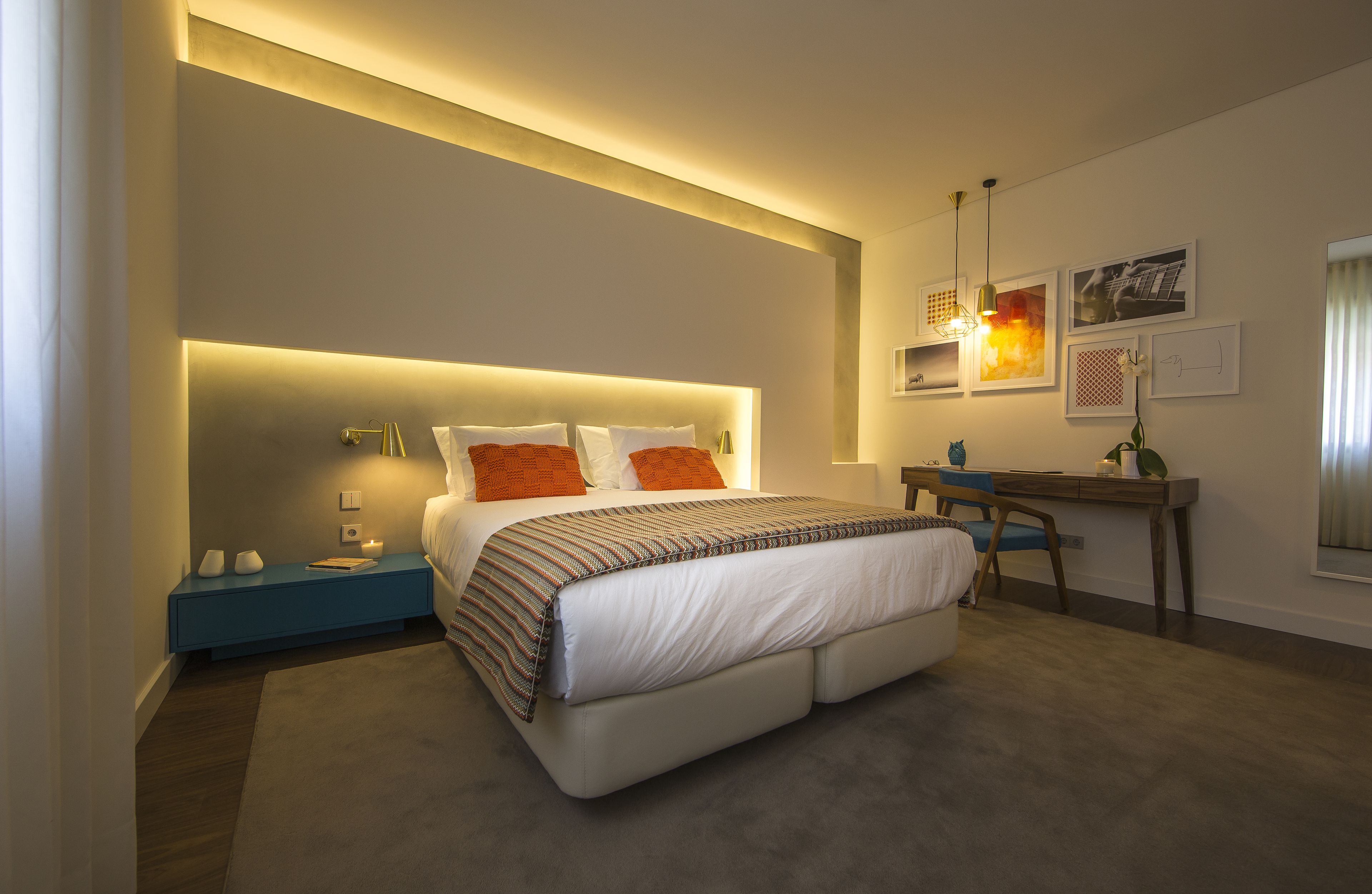 A modern hotel room with a large bed, bedside tables, a desk, and a chair.