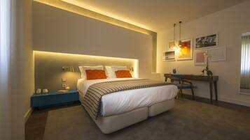 A modern hotel room with a large bed, bedside tables, a desk, and a chair.