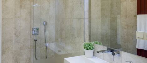 A modern bathroom with a glass-enclosed shower, a wooden vanity with a white sink, and a mirror above the sink.