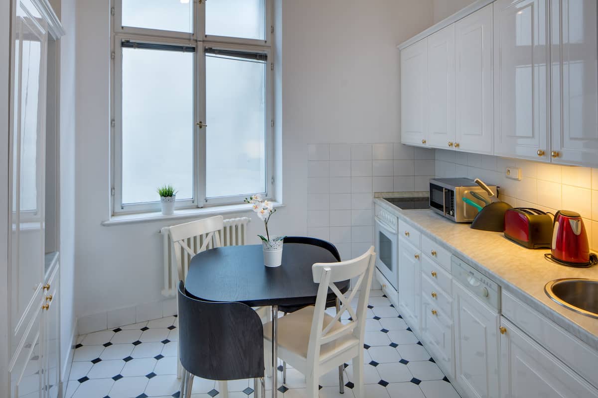Eine Küche mit weißen Schränken, einem schwarzen Tisch und einem Fenster mit Blick.