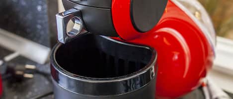 Una màquina de cafè vermella i negra amb una tassa col·locada a sota.