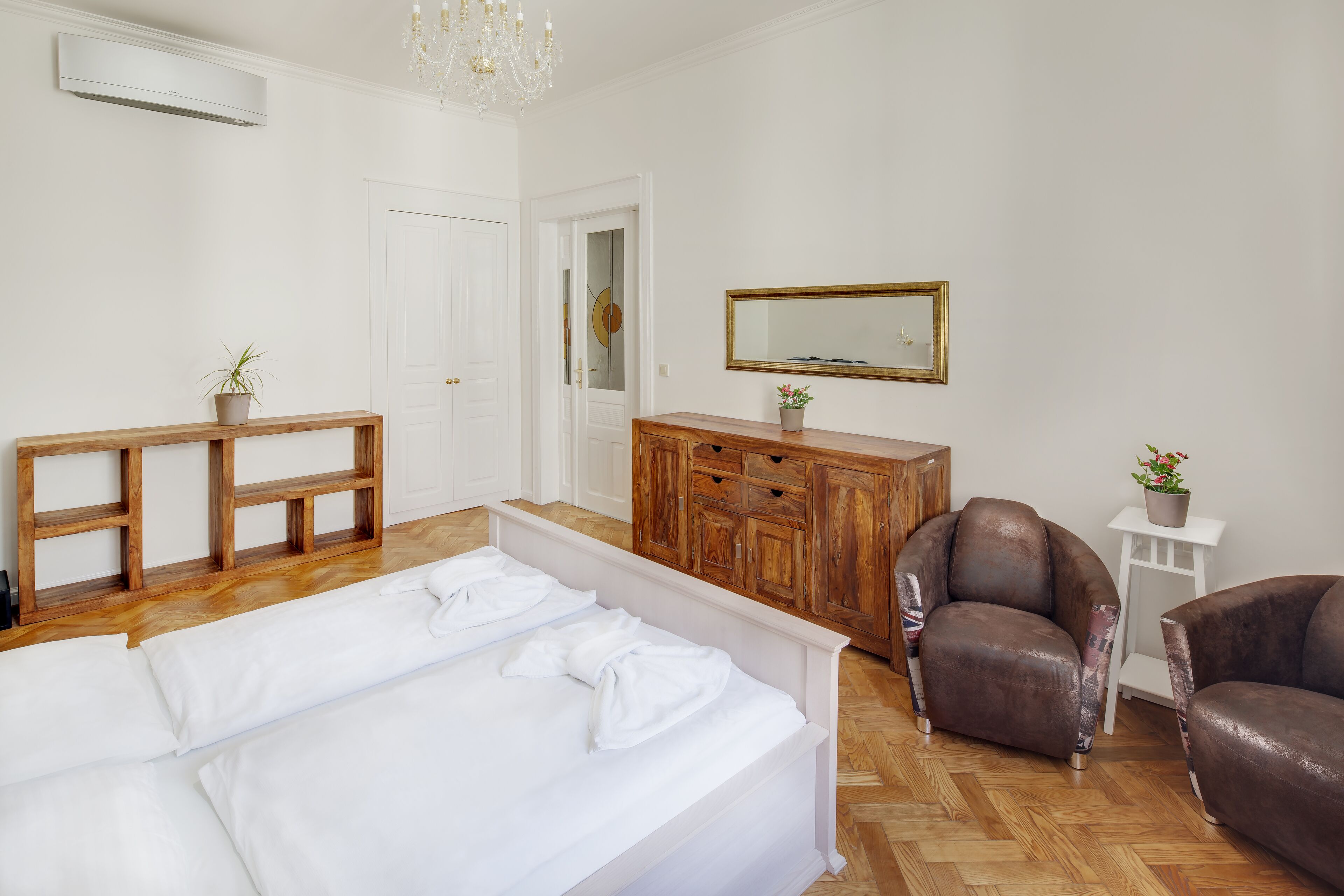 Un dormitorio con cama, muebles de madera, un espejo y una araña.