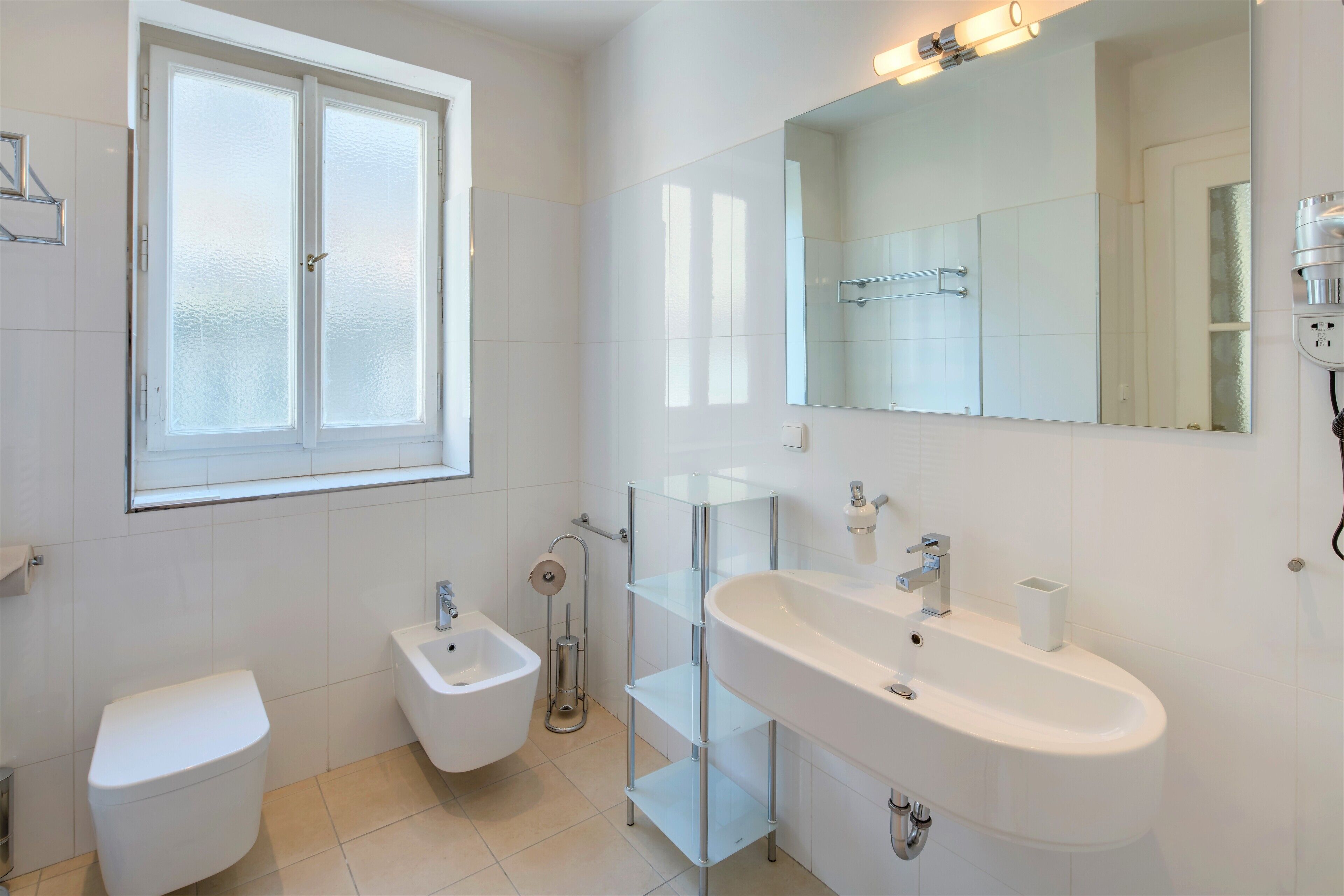 Ein modernes Badezimmer mit Toilette, Bidet und einem großen Waschbecken mit Spiegel darüber.