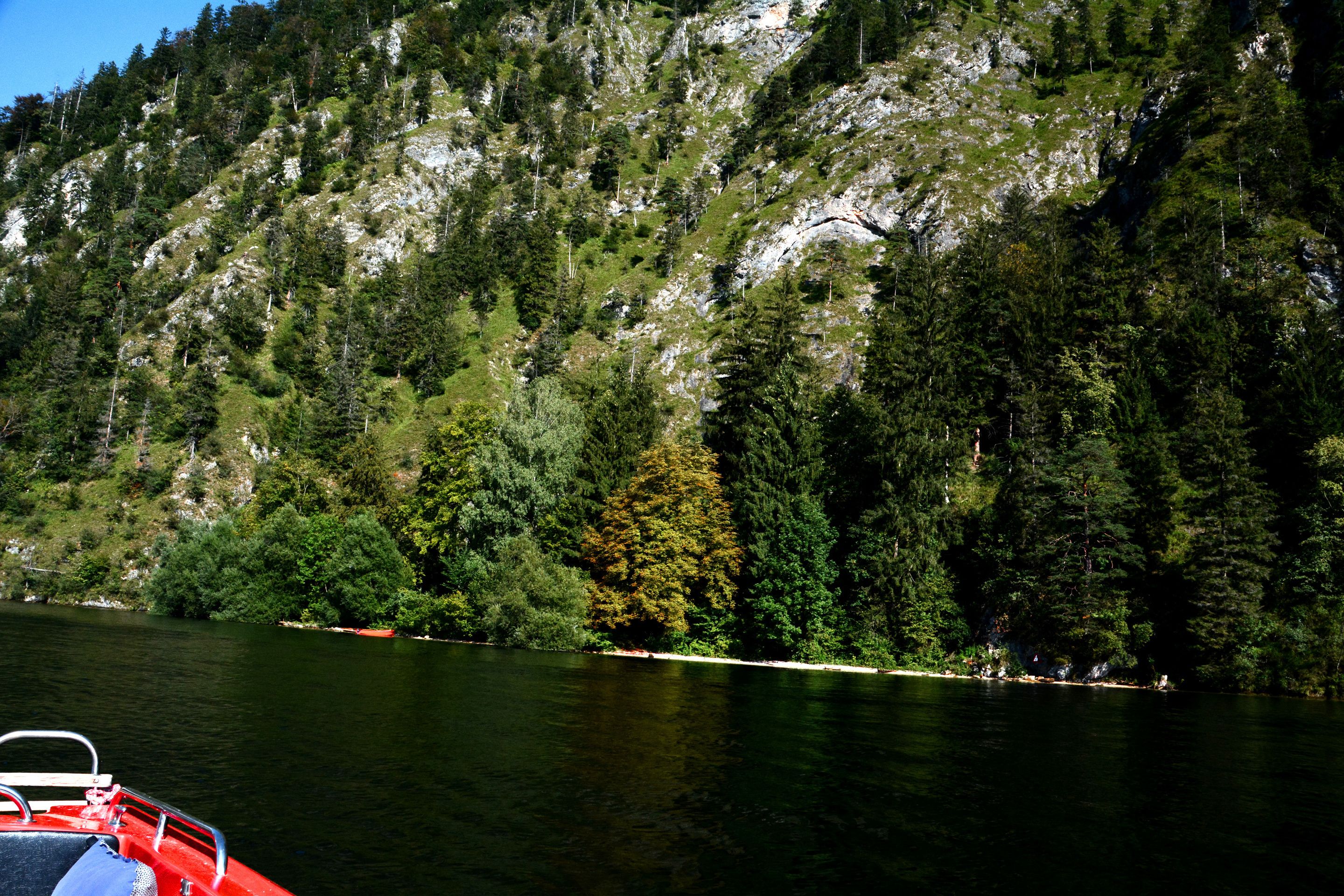 A boat on a calm lake with a forested mountain in the background.