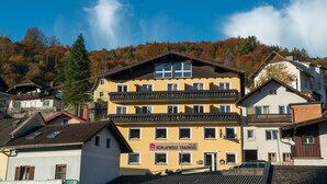Un hotel de varios pisos con balcones, un letrero que indica que es un hotel y vistas a una ladera boscosa.