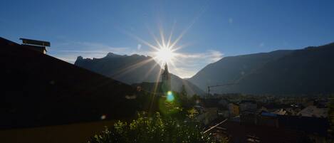 A mountain landscape with a clear sky and the sun shining brightly.
