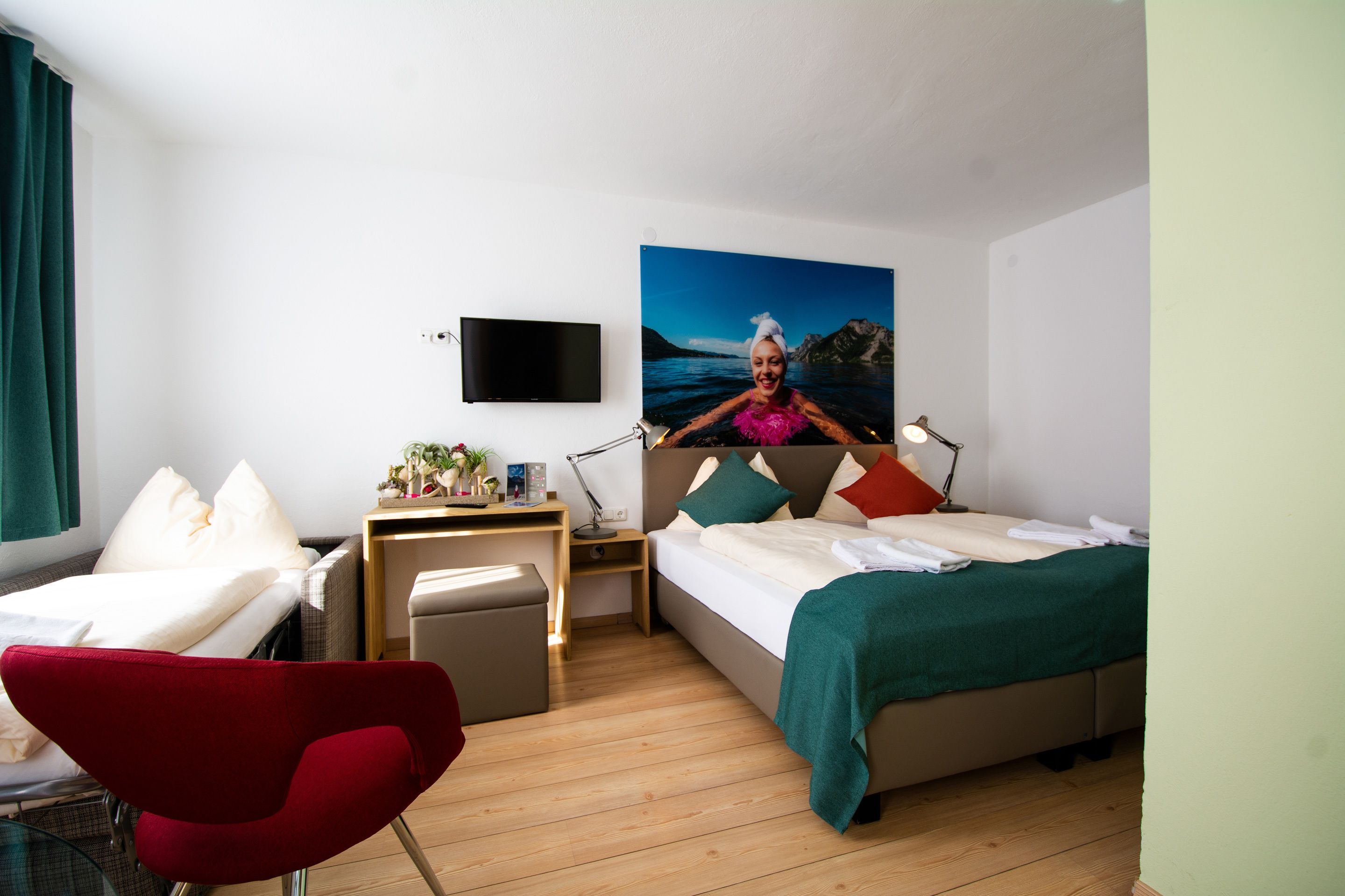 A modern hotel room with a bed, a desk, a chair, and a TV.