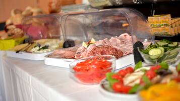 A buffet table with various food items including meats, cheeses, and salads.