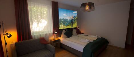 A hotel room with a bed, a sofa, a TV, and a lamp.