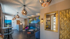 Un interior moderno con una zona de bar, asientos y un mural de un paisaje montañoso.