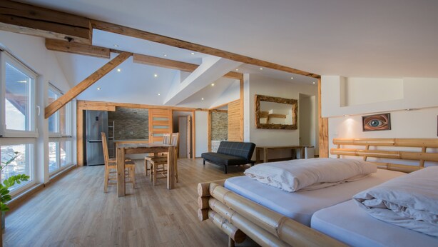 Una habitación amplia con una cama grande, un comedor y una cocina.