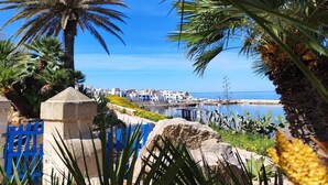 A coastal view with palm trees, a clear blue sky, and a marina with boats. - Marettimo Residence (Marettimo)