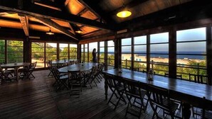 A restaurant with wooden tables and chairs, large windows offering a view of the ocean. - Marettimo Residence (Marettimo)